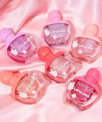 A set of six colorful and highly pigmented Huda Moji lip oil bottles held in a hand.