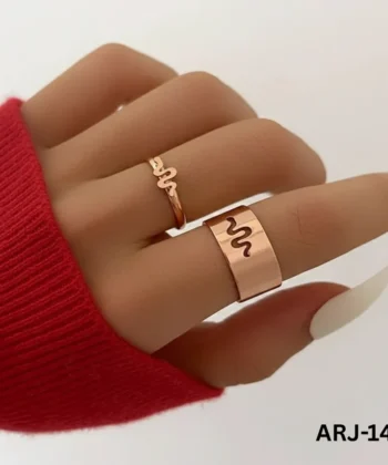 A hand wearing a gold-toned serpent duo ring set, featuring a thin snake-shaped ring and a wide band with a snake cutout.