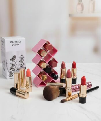 A premium teal-colored 10-grid vertical lipstick organizer with a honeycomb structure, shown alongside its retail packaging and a pink makeup brush on a marble surface to demonstrate size and style.