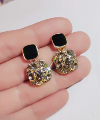 pair of large square-shaped drop earrings with a black top stud and a gold-toned base encrusted with smoky crystals.