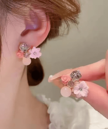 Close up of a woman's ear wearing a pink floral crystal stud earring