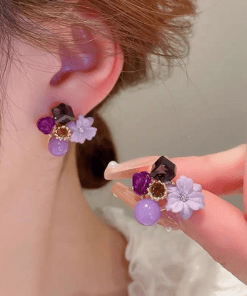 Close up of a woman's ear wearing a pink floral crystal stud earring