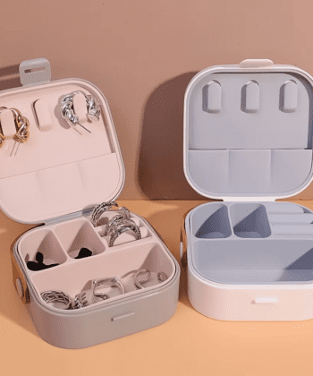 Two compact square jewelry boxes (one white, one orange) with "MINI BOX" labels and brown carrying handles.