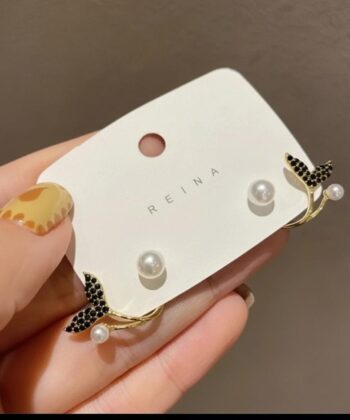 Woman wearing a golden mermaid fish tail earring with pearl accents