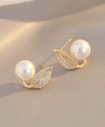A pair of gold leaf-shaped earrings encrusted with small zircons with a white pearl sitting on the curve.