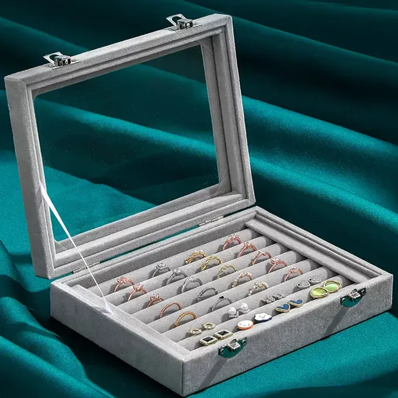 Mistico Velvet Jewelry Organizer. Grey velvet jewelry box with glass lid showing rings and earrings inside.