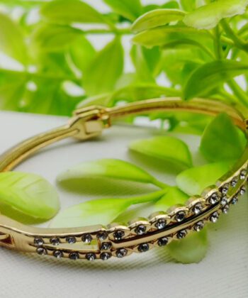 Gold-plated bracelet featuring a crystal-studded oval motif and central gold bar.