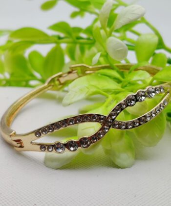 Gold-plated bracelet featuring a crystal-studded infinity twist design.
