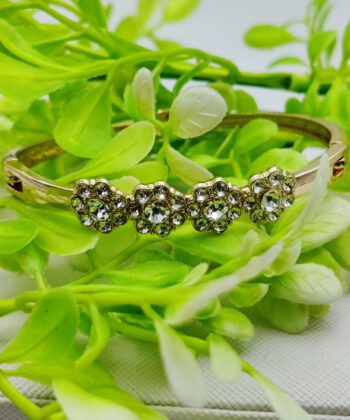 Gold-plated bracelet with three crystal-studded floral motifs.