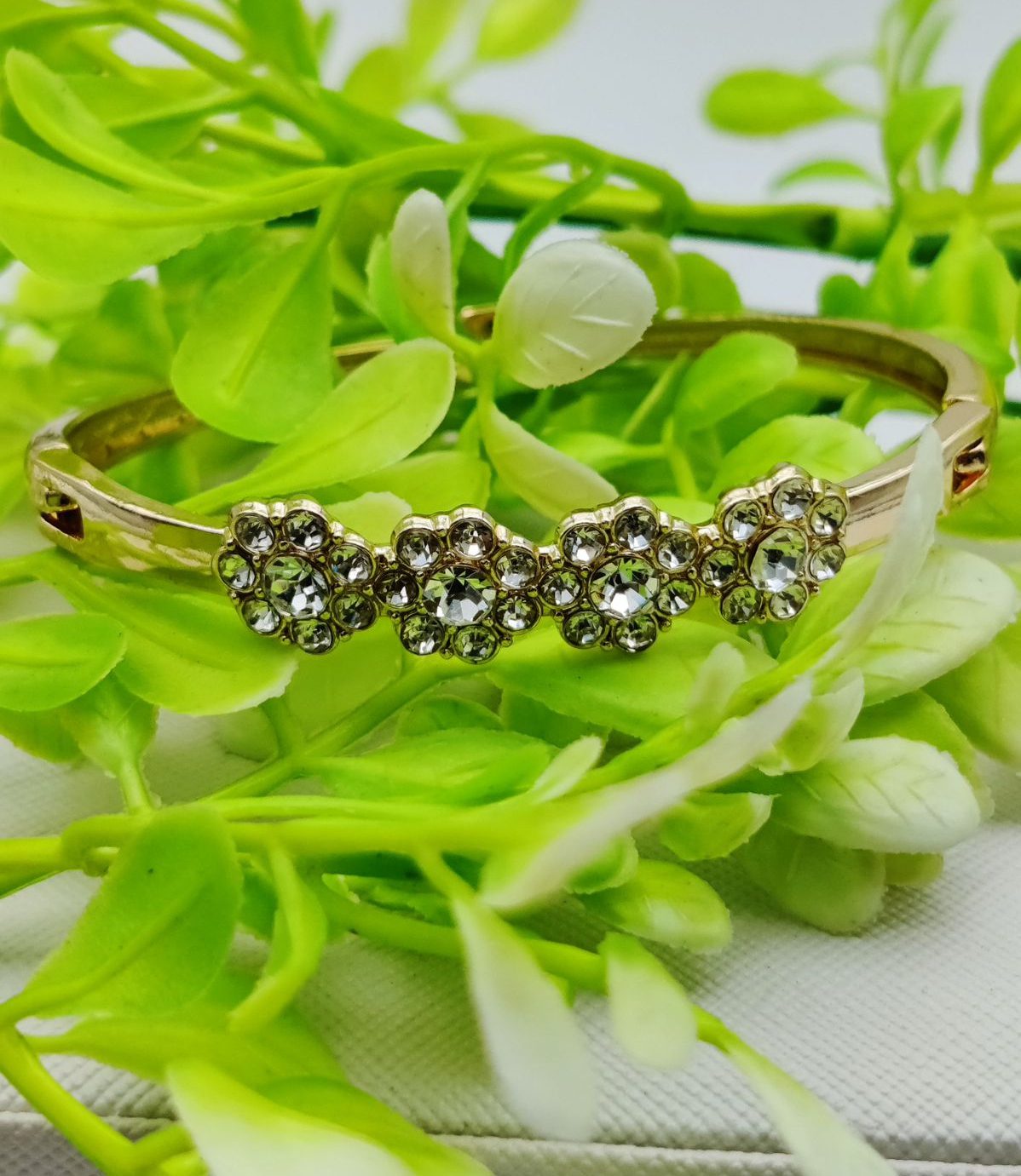 Sparkling Floral Trio Crystal Bracelet. Gold-plated bracelet with three crystal-studded floral motifs.