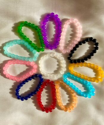 Multiple colorful beaded stretch bracelets displayed in a circular pattern on a white surface.